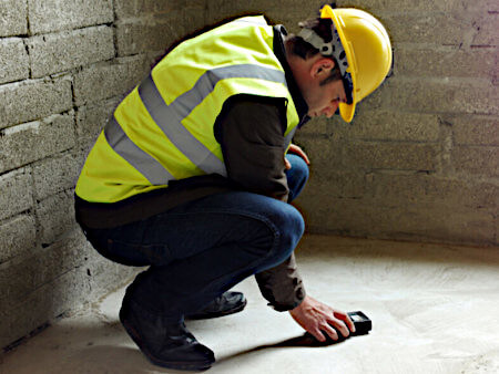 This is a picture of a man testing moisture in a concrete slab using a moisture meter